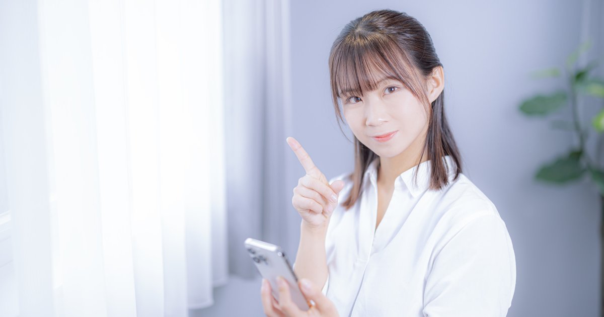 スマホを手に人差し指を立てて案内する女性