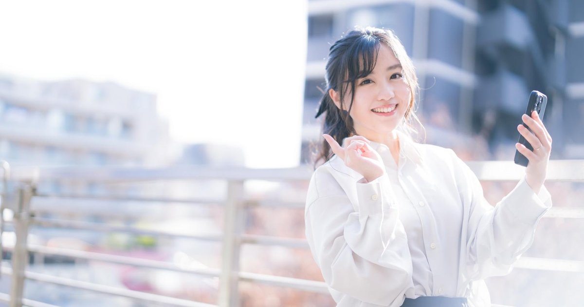 屋外でスマホを手に笑顔の女性