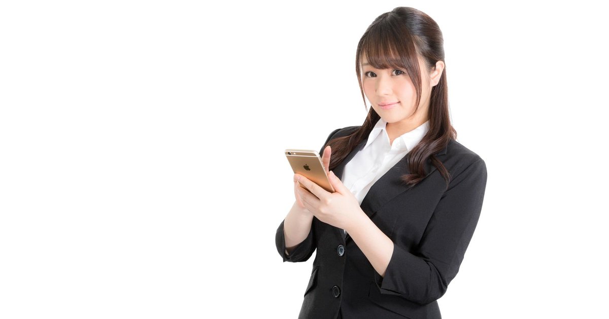スマホを手に微笑む黒いスーツの女性